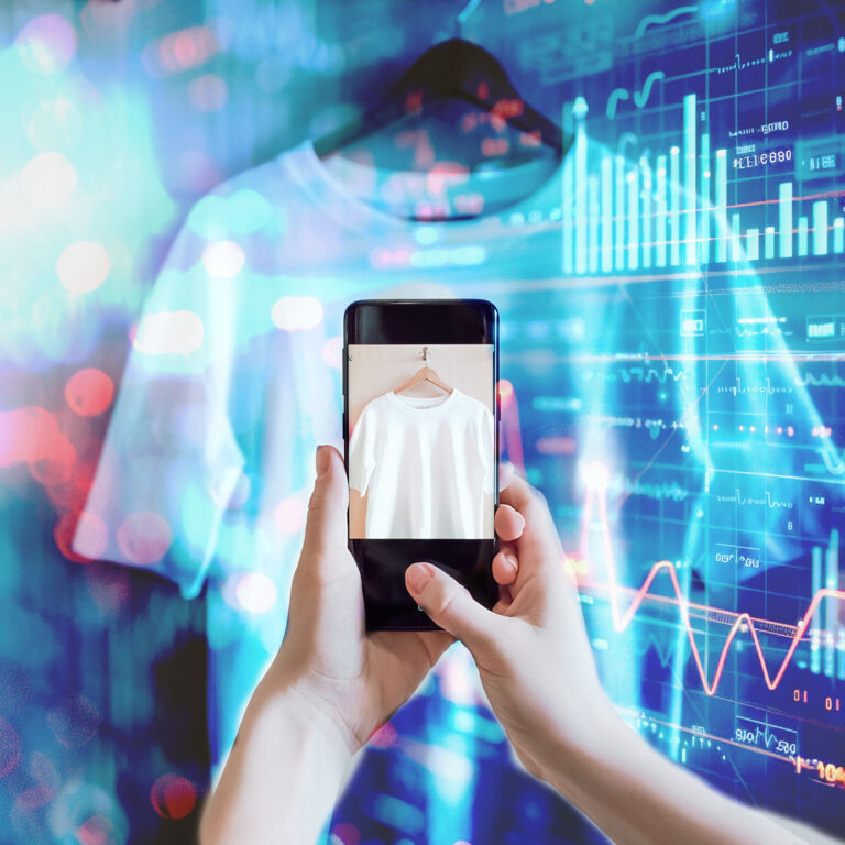 Conceptual image illustrating clothing product photography with technology. A person holds a smartphone, capturing a photo of a white T-shirt on a hanger. In the background, there’s a mix of blurred graphics and digital data, including charts and lines, symbolising the integration of technology and e-commerce in product photography.